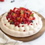 Pavlova aux fruits rouges avec chantilly et fruits frais sur un plat